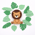 Fondant lion cake topper surrounded by fondant green leaves on a white background